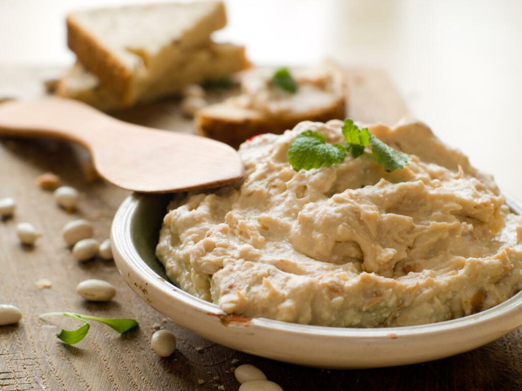 Bowl of fresh hummus dip with bread slices, selective focus