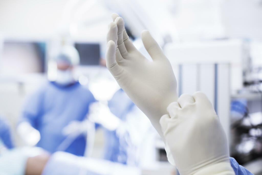 Close-up of surgeon putting on surgical gloves in operating theater