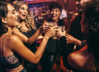 Nove ugotovitve: Alkohol je bolj nevaren za ženske Group of friends partying in a nightclub and toasting drinks. Happy young people with cocktails at pub.