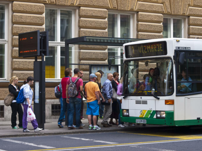 Ljubljana, Slovenia - july 26, 2011: A view of the people in line and slowly going on the bus at bus station in front of main Post office in center of Ljubljana. On left side is panelwith bus line nimber and time when it will leave.