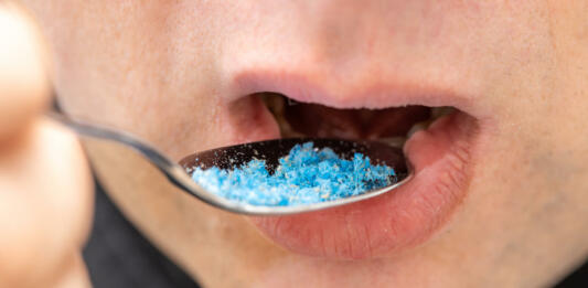 Microplastic in food, Environment and health concept, Person putting a spoon with plastic particles in his mouth