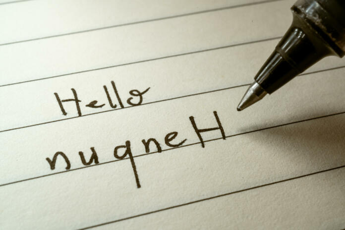Nerd lerning Klingon language writing Hello nuqneH word in Klingonese on a notebook close-up shot