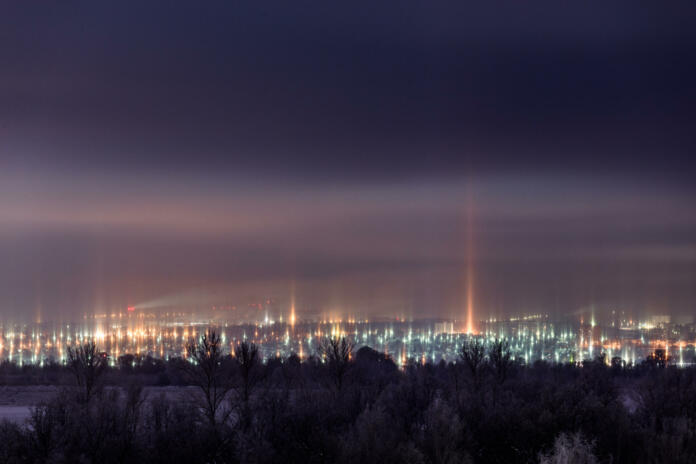 night winter cityscape with light pillars atmospheric phenomenon.