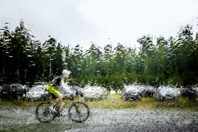 Revda, Russia - July 31, 2016: blurred silhouette behind squirt water glass of mountainbiker during Regional competitions on cross-country bike