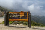 Skagway, Alaska, USA - July 20, 2011: Klondike highway to Canada. Colorful Welcome sign near the border. Cloudscape in back.