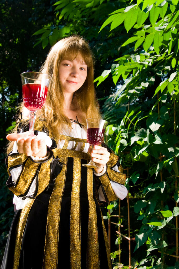 Smiling young woman in renaissance dress with wine