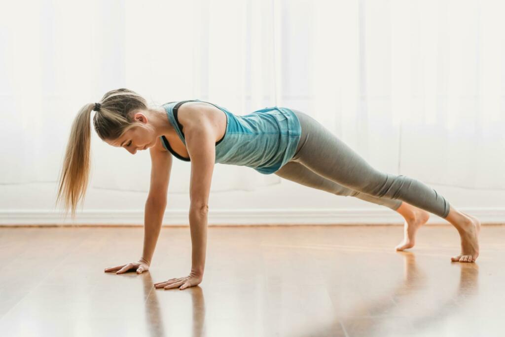 Sportive woman doing plank in room