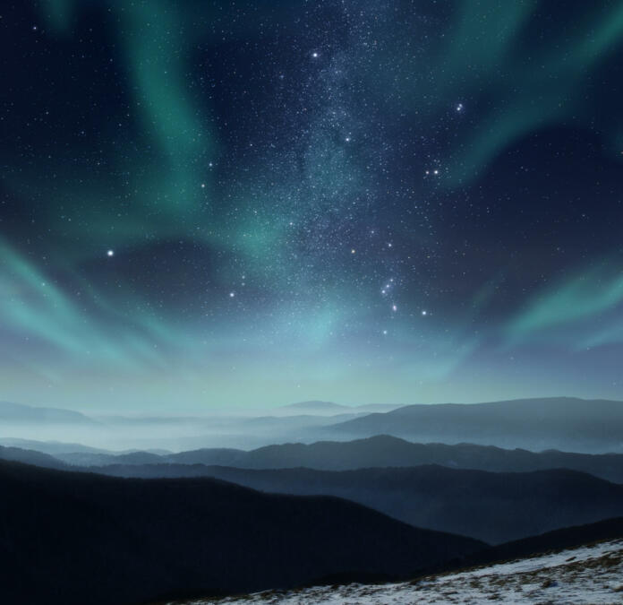 Starry night sky with aurora polaris over the mountains