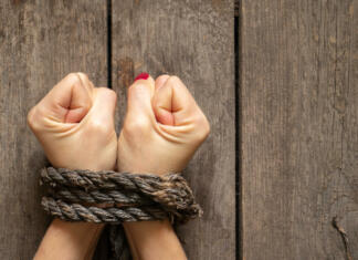 Kako je aplikacija ustavila trgovanje z ljudmi? tied female hands with rope on wooden background close up