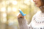 Woman hand holding asthma inhaler ready to use in winter