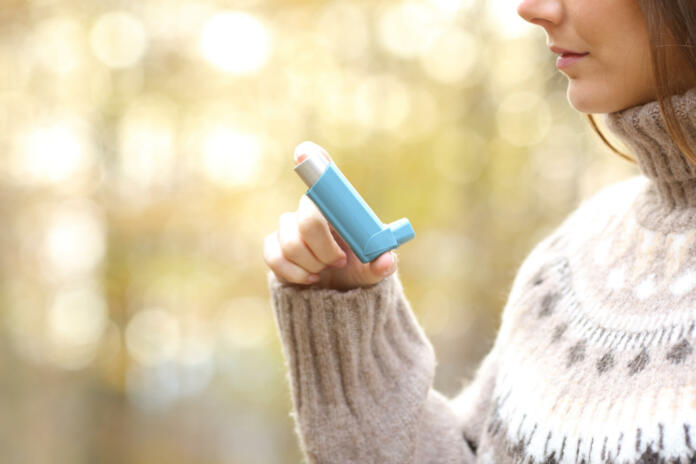 Woman hand holding asthma inhaler ready to use in winter