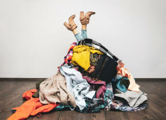 Kaj narediti s starimi in rabljenimi oblekami? woman legs out of a pile of clothes on the floor. shopping addiction concept