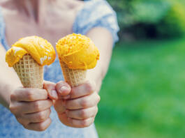 Woman's hands holding refreshing ice cream in waffle cones treats with a hint of zesty lemon flavour. With copy space