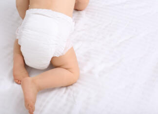 Grozljiv podatek! Toliko let se v naravi razgrajujejo klasične plenice Back view of cute baby in dry soft diaper on white bed, closeup. Space for text