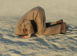 Zakaj je človeštvo vse bolj neumno? Businessman with head stuck in sand at the beach