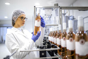 Female factory expert controlling wine production in alcohol beverage bottling plant.