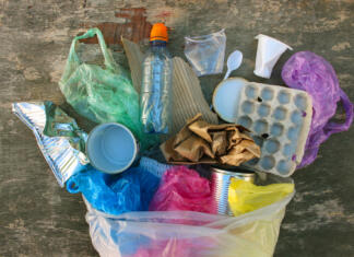 Prihajajo prepovedi, ki bodo spremenile način nakupovanja in delovanja restavracij Garbage bag with different trash on wooden background. Top view. Flat lay.
