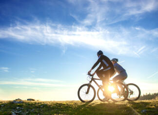 S temi nasveti boš na kolesu bolje poskrbel za lastno varnost Happy mountain bike couple outdoors have fun together on a summer afternoon sunset.