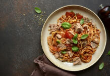 Ko zmanjka idej za kosilo: preprost recept s tuno, ki navduši Italian pasta spaghetti with tuna in tomato sauce on a dark slate, stone or concrete background. Top view with copy space.