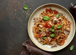 Ko zmanjka idej za kosilo: preprost recept s tuno, ki navduši Italian pasta spaghetti with tuna in tomato sauce on a dark slate, stone or concrete background. Top view with copy space.