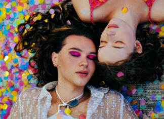 Moda nove generacije: brezspolna moda ali ‘genderless fashion’ Overhead view of two non-binary friends lying down side by side, wearing bright makeup with fallen confetti and eyes closed