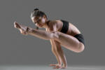 Portrait of beautiful young fit woman in sportswear shorts doing sport exercises, handstand Tittibhasana, Firefly posture, full length, side view, studio image on gray background