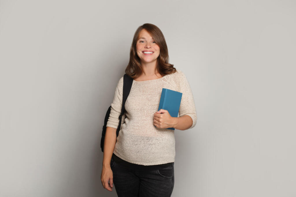 Pregnant woman student standing against white background