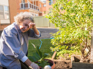 Senior woman rubbing forehead while gardening outdoors - tiredness concept (selective focus)