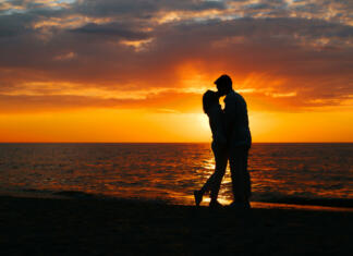 Kako postati ljudem bolj privlačen? Kaj pravi teorija privlačnosti Silhouette of a happy young couple in love kissing on seashore at sunset, copy space. Flirt, romance, relationship, date, valentines day concept.