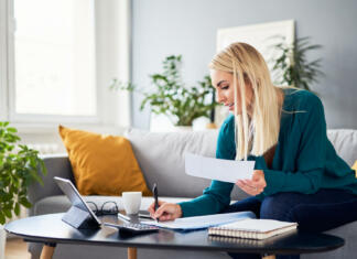 Koliko časa je treba hraniti račune? Smiling woman analysing bills filling tax documents while at sitting on sofa at home