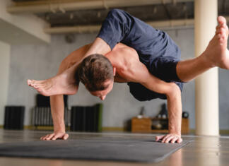Joga poze, ki se jih lotevajo le mojstri Strong male yogi standing on his hands with both feet in the air indoors