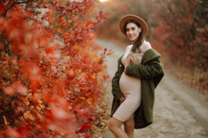 Stylish pregnant woman walks in an autumn park, happily expecting a baby. Happy pregnancy. Motherhood. Autumn season.