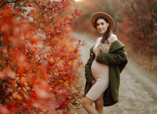 Kakšen naj bo tvoj nosečniški stil oblačenja za na faks (udobno na predavanja)? Stylish pregnant woman walks in an autumn park, happily expecting a baby. Happy pregnancy. Motherhood. Autumn season.