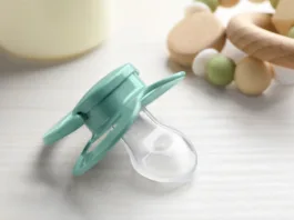 Baby pacifier on white wooden table, closeup