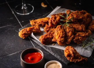 Zakaj smo nori na pečene perutničke? Buffalo style chicken wings served with cold beer on dark background