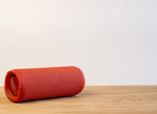 5 ključnih nasvetov pri nakupu bluetooth zvočnikov Red bluetooth speaker on wooden table with white background. Space for texture.