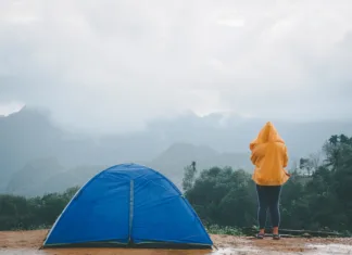Nasveti za kampiranje v dežju: kaj narediti, če te med kampiranjem čakajo plohe Woman camping blue tent on mountain peak and enjoying beautiful nature of hills and during rainy season at Doi Tapang, Sawi District, Chumphon, Thailand.