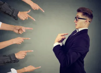 S tem početjem je vsak od nas glavni krivec za emisije v potniškem prometu Blaming you. Anxious man judged by different people pointing fingers at him. Negative human emotions feeling