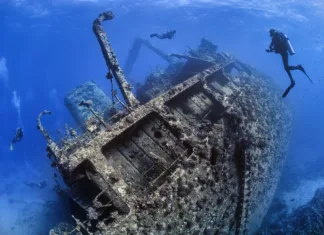 Najbolj impresivne potapljaške destinacije – dih jemajoči prizori Divers exploring the outside of a shipwreck
