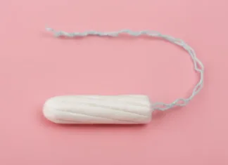 Srhljivo! V tamponih našli toksične kovine – kako nevarno je? Medical female tampon on a pink background. Hygienic white tampon for women. Cotton swab. Menstruation, means of protection. Tampons on a red background.