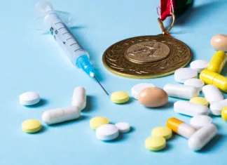 Najbolj čudaški (in ogaben) način dopinga – so ga uporabili kolesarji na letošnjem Touru? Syringe, medals and pills on a blue background. Doping in sports. Abuse of anabolic steroids for sports. Sports fraud. Doping athletes.