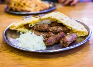Študentski bon inšpektor: Leskovački dvor Traditional bosnian barbecue dish cevapi served with somun and chopped onions. Famous balkan BBQ dish served on an inox plate in Bascarsija, Sarajevo, Bosnia and Herzegovina.