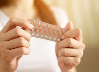 Mineva 64 let od uporabe prvih kontracepcijskih tablet Woman hands opening birth control pills in hand. eating Contraceptive pill. Contraception reduces childbirth and pregnancy concept.