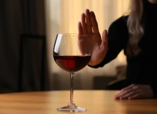 Kaj je bolj nevarno: alkohol, heroin ali kokain? Woman refusing to drink red wine at home, closeup. Alcohol addiction treatment