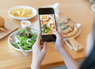 Točke za brezglutenski obrok: Kako so ocenjeni ponudniki študentske prehrane? (#Komentar) Woman take picture of a meal on the table after ordering food online to eat at home. Photography and use phone concepts