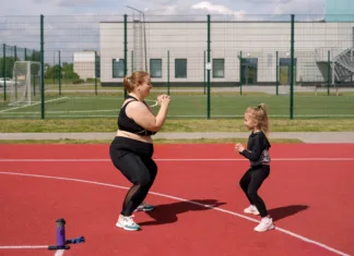 Je za debelost kriva neaktivnost matere med nosečnostjo? Young mother and skinny daughter play sports together, doing squat exercises on sports field. Plump woman with merrily laughing child. Girl supports mother in effort to lose weight. Outdoor fitness
