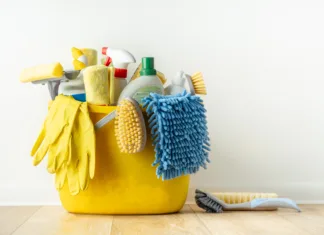 Ta vsakdanji izdelek za čiščenje sprošča bilijone vlaken mikroplastike Brushes, bottles with cleaning liquids, sponges, rag and yellow rubber gloves on white background. Cleaning supplies in the yellow bucket on the wooden floor. Cleaning company service advertisement
