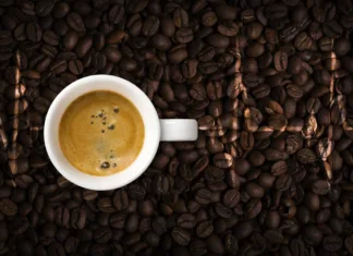 Ali je brezkofeinska kava zdrava? Coffee cup and cardiogram on coffee beans background. View top