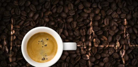 Coffee cup and cardiogram on coffee beans background. View top