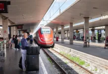 Zaplet na vlaku: Zaradi neprimernega vedenja italijanskih najstnikov posredovalo celo veleposlaništvo FLORENCE, ITALY - JUNE 15, 2024: Picture of a frecciarossa train entering Florence train station. Frecciarossa is a high-speed train of the Italian national train operator, Trenitalia, as well as a member of the train category Le Frecce. The name was introduced in 2008 after it had previously been known as Eurostar Italia. This photograph captures the arrival of a Frecciarossa train from Trenitalia at the Firenze Santa Maria Novella station. The sleek, modern design of the train highlights the advanced technology and efficiency of Italy's high-speed rail system. Passengers are seen waiting on the platform, ready to embark on their journey, showcasing the importance of rail travel in connecting cities across Italy. The image reflects the dynamic and fast-paced nature of transportation in one of Italy's major transit hubs.